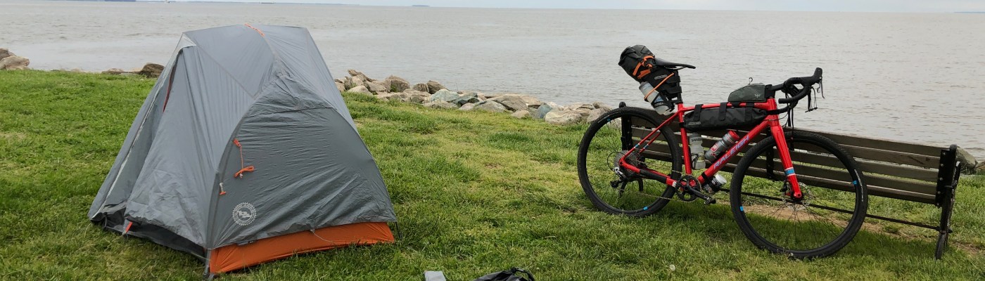 A bike and tent on the lawn by the bay